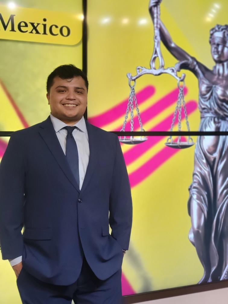 Michael Martinez, founder of Martinez Law, wearing a navy suit beside a Lady Justice display